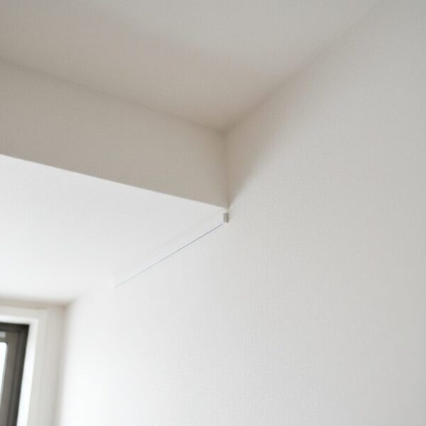 部屋の天井と壁の境目に沿って、白い配線モールでLANケーブルを隠している様子。視線が届きにくい壁の角や天井を利用して、配線を目立たなくする賃貸向けのスマートなテクニック。