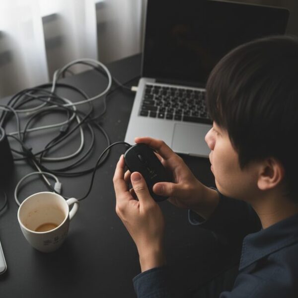 デスクの上で裏返された有線マウスのセンサーが全く光っていない状態。USBポートからの電力供給不足やケーブル断線といった物理的な故障の可能性。